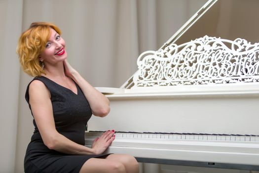 Beautiful young woman near a white grand piano.