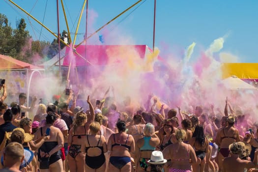 Ukraine, Iron Port - August 24, 2020: A large group of people at a festival of colorful colors holi on the beach on the seashore.