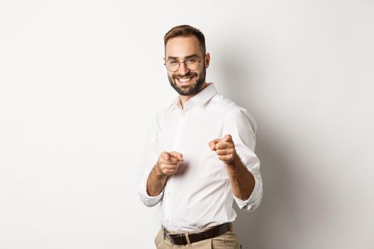Confident businessman smiling, pointing fingers at you, congrats or praise gesture, standing over white background