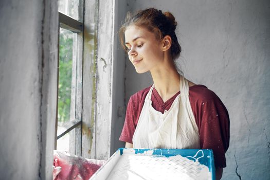 woman in apron painter repair painting window