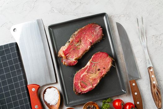 Marinated raw steaks on stone table with spices