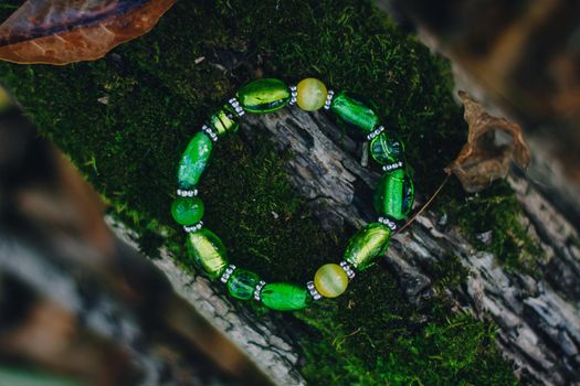 Bracelet handmade handcrafted do-it-yourself glass jewelry on natural wood forest background. Business idea, earning money for a hobby. Useful quarantined skills