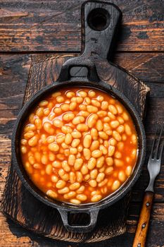 Beans in tomato sauce in a pan. Dark wooden background. top view