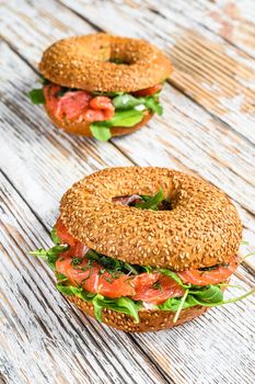 Bagels with salmon, cream, avocado and arugula. White wooden background. Top view