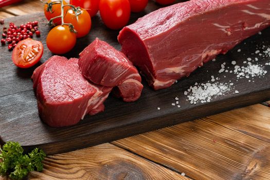 Slices raw meat fillet on wooden board
