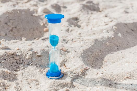 Hourglass close-up stand on white beach sand background
