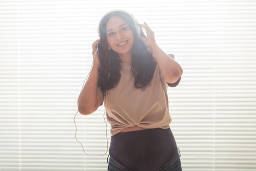Beautiful young peaceful pregnant woman listens to pleasant classical music using smartphone and headphones. Concept of positive attitude before childbirth