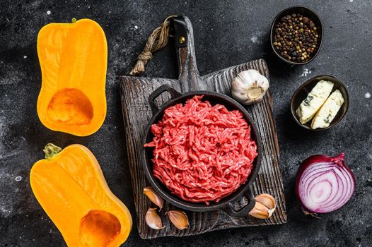 Raw mince meat, pumpkin with garlic and onion. Black background. Top view