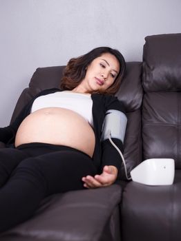 Pregnant woman measures blood pressure with sphygmomanometer