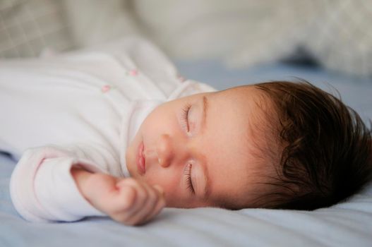 Newborn baby girl sleeping on blue sheets