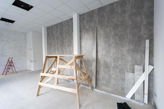 Repair in the apartment. building painter's goat in the interior of a bright room with fresh plastered walls. White walls in a building construction house.