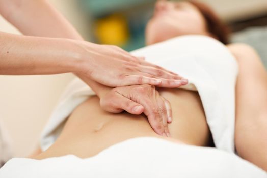 Therapist applying pressure on belly. Hands massaging woman abdomen.