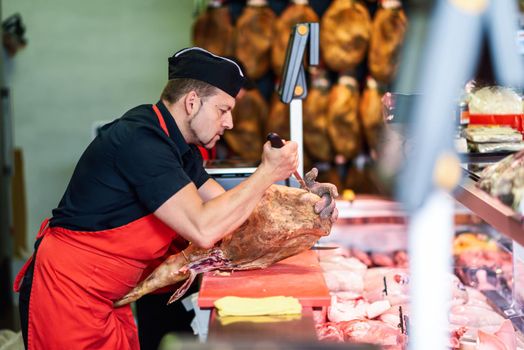 Butcher boning a ham in a modern butcher shop