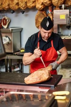 Butcher boning a ham in a modern butcher shop