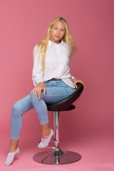 Cute Smiling Blonde Girl Sitting on High Chair in Studio