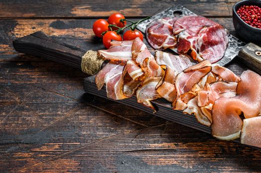 Meat antipasto board, pancetta, salami, sliced ham, sausage, prosciutto, bacon. Dark Wooden background. Top view. Copy space