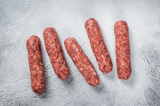 Raw beef and lamb meat kebabs sausages on a butcher table. White background. Top view