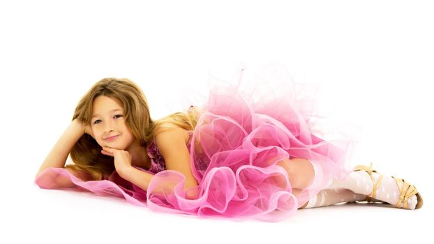A little girl is lying on the floor. Studio photo session on a white background.