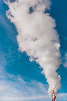Environmental pollution, environmental problem, smoke from the chimney of an industrial plant or thermal power plant on a background of blue sky with clouds