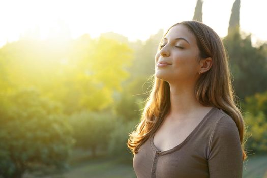 Happy woman breathing fresh air against natural background. Copy space.