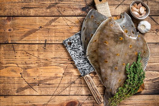Raw flounder flatfish on butcher board with cleaver. wooden background. Top view. Copy space
