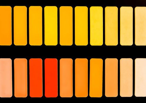 Samples of different shades of red, yellow and orange in squares on a black background, colorful bright abstract mosaic texture