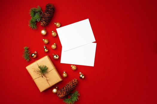 Blank sheet of paper and wrapped present for Christmas celebration on red background top view