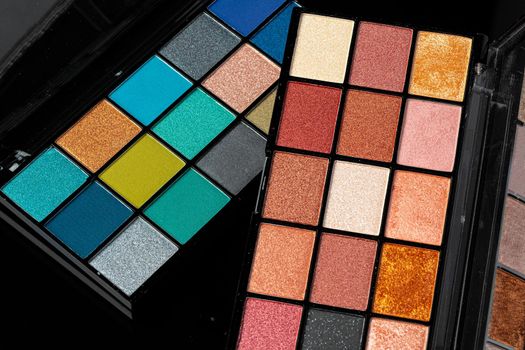 Professional pallet of eyeshadow. Multicoloured crumbled eye shadows on black table.