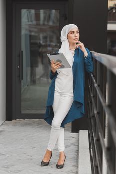 Modern Arabian muslim woman with tablet computer outdoors