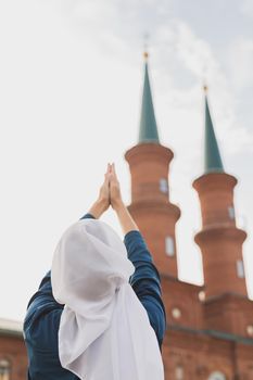 Muslim woman prayer wear hijab fasting pray to allah on mosque background, back view