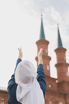 Muslim woman prayer wear hijab fasting pray to allah on mosque background, back view