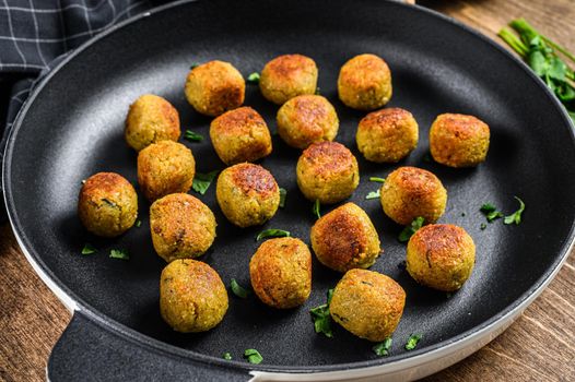 Fried Vegetarian falafel balls from spiced chickpeas in a pan. Wooden background. Top view