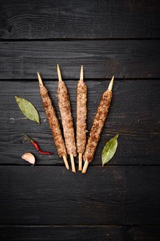 Kofta or lula beef and lamb meat kebabs skewers, on black wooden table background, top view flat lay, with copy space for text