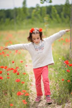 Cute little girl having fun in a poppy field
