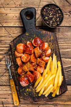 Curry wurst Sausages with French fries on a wooden board. wooden background. Top view