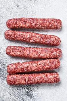 Fresh raw beef meat kebabs sausages. White background. Top view