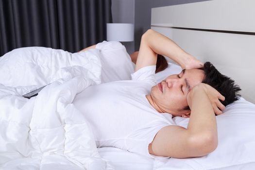 man having sleepless on bed and having migraine,stress, insomnia, hangover in bedroom