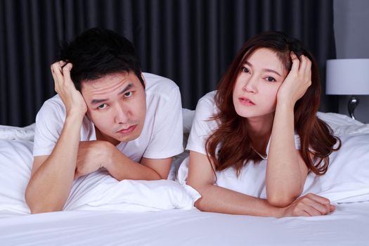 young depressed couple on bed in bedroom