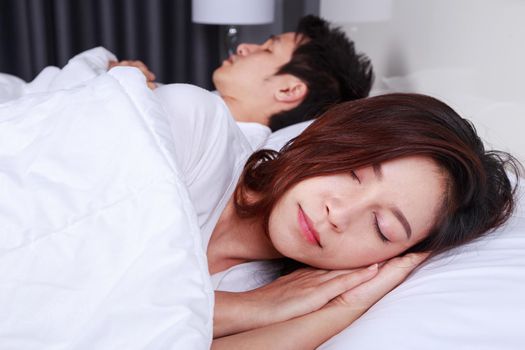 young woman sleeping with her husband in a bed at home