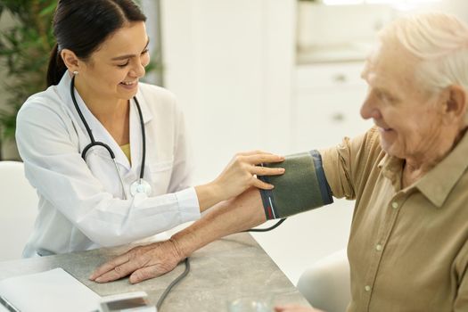 Friendly medical staff measuring blood pressure of a senior citizen