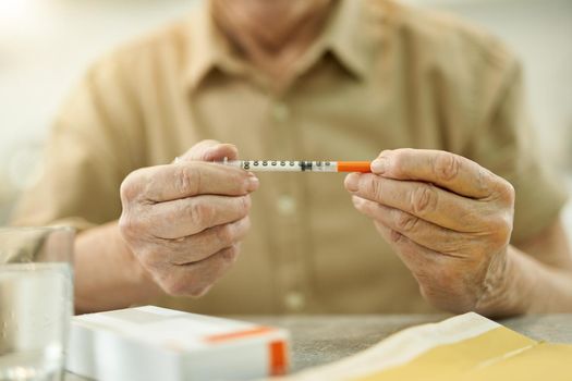Senior citizen hoding a thin syringe while at home
