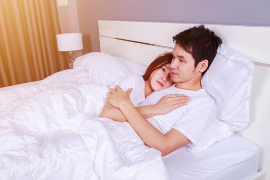 happy young attractive couple hugging on bed in bedroom