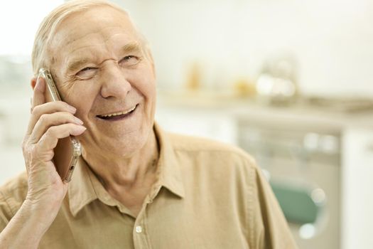 Joyous aged gentleman having a pleasant phonecall
