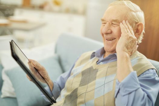 Happy elderly man consulting online with a therapist at home