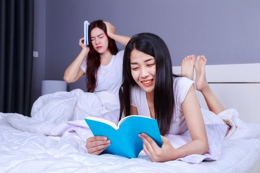two woman reading a book on bed in bedroom