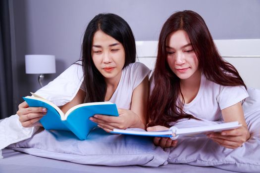 two woman reading a book on bed in bedroom