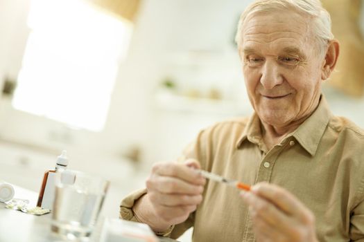 Elderly grandpa studying a medical syringe in his hands