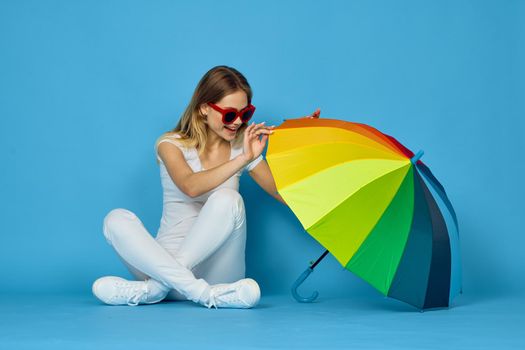 fashionable woman with umbrella rainbow colors posing blue background