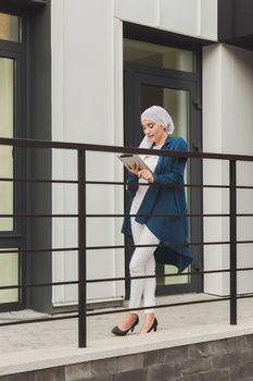 Beautiful Asian businesswomen wearing hijab using her tablet at outdoor.