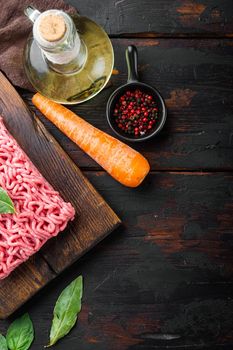 Ingredients for cooking Bolognese sauce, minced beef meat tomatoe and herbs, on wooden cutting board, on old dark wooden table background, top view, flat lay, with copy space for text